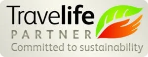 Best travel agency in Greece Logo du partenaire Travelife avec le texte « Engagé pour le développement durable », accompagné d'un motif de feuille verte et rouge. Idéal pour promouvoir des circuits en petits groupes en Grèce, en particulier dans le nord de la Grèce, ou un roadtrip écologique à travers le pays. Offbeat-Travel